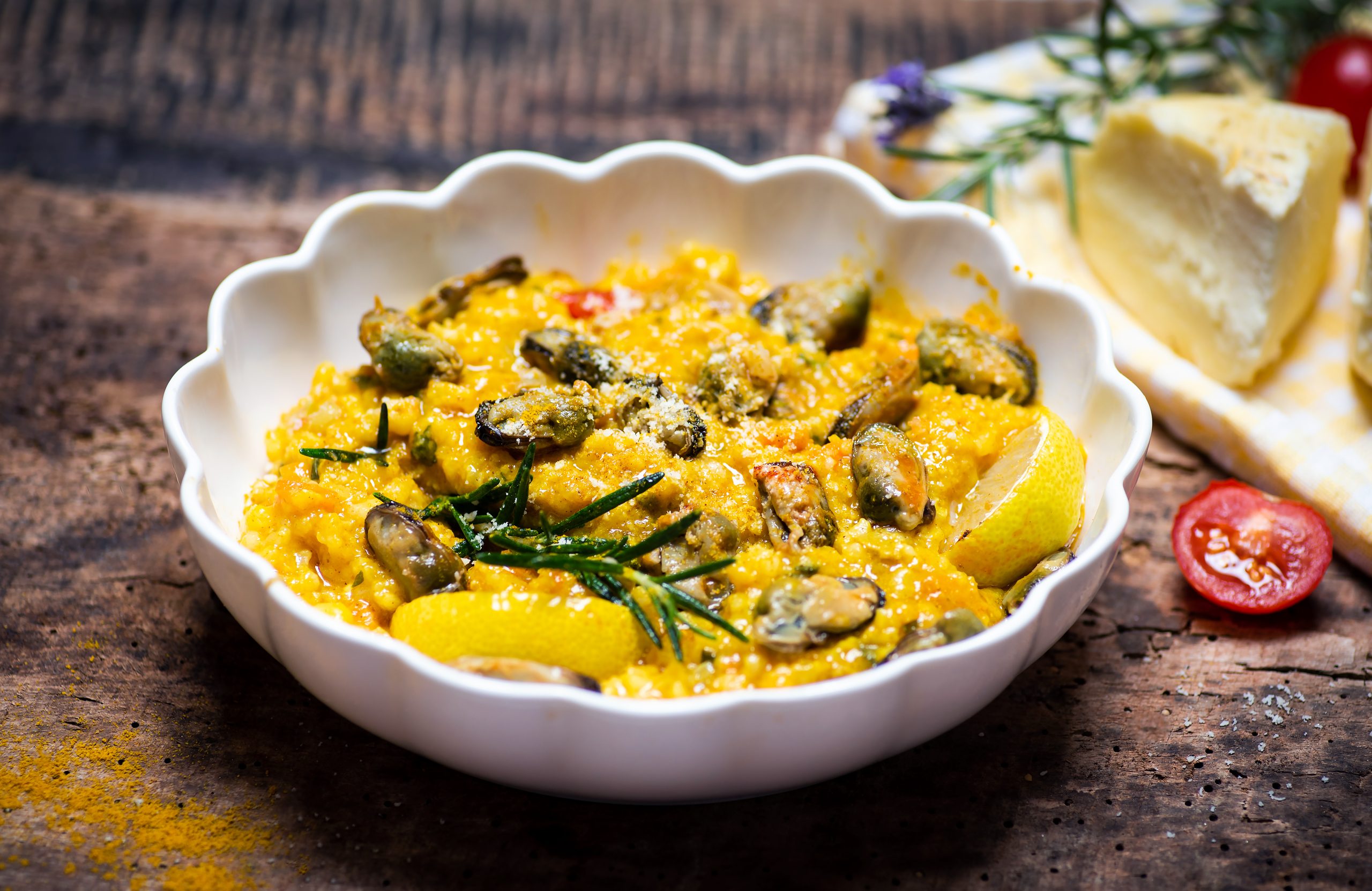 Meal with risotto and mussels in a white bowl.
