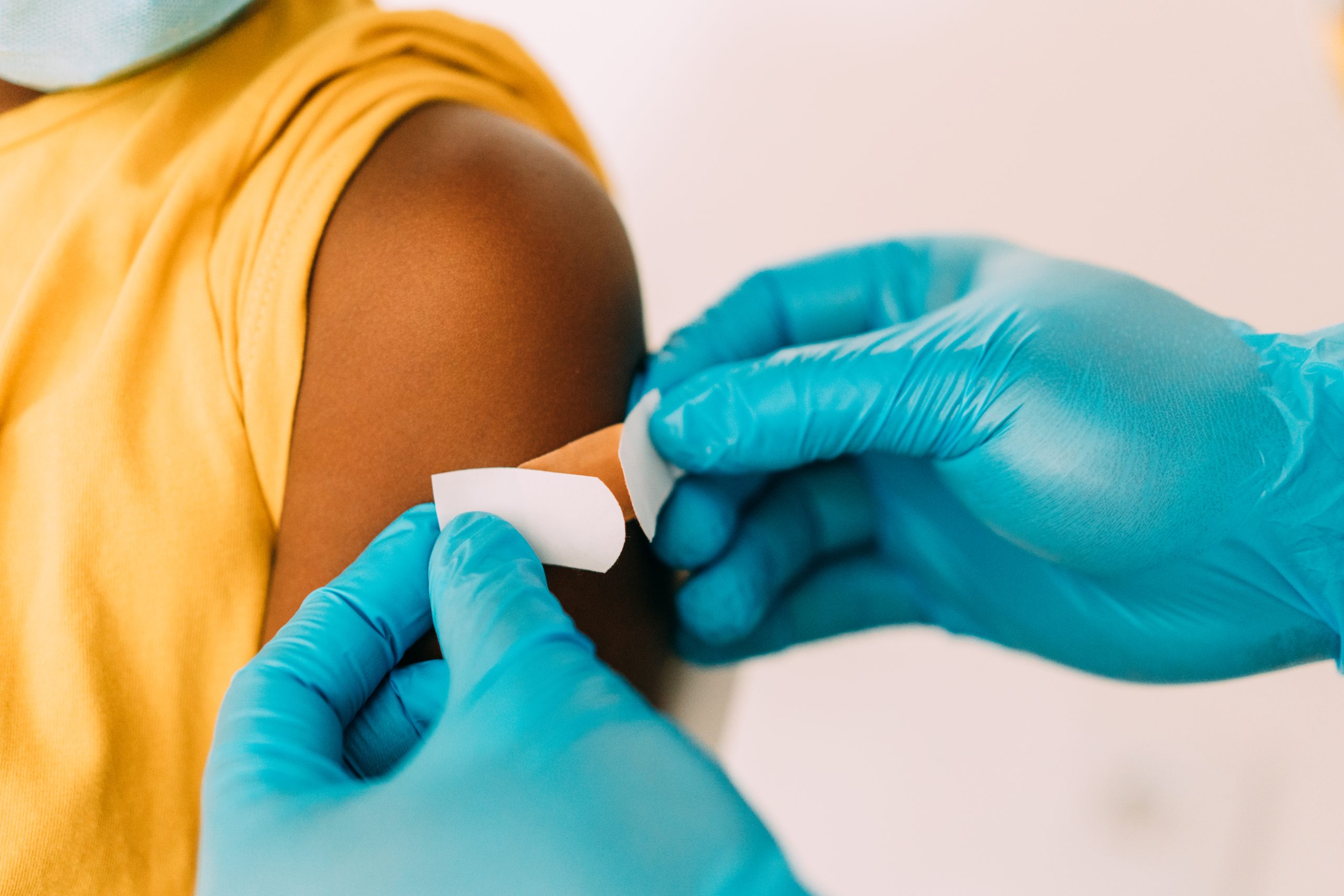 Healthcare professional putting a band-aid on a patient’s upper arm.