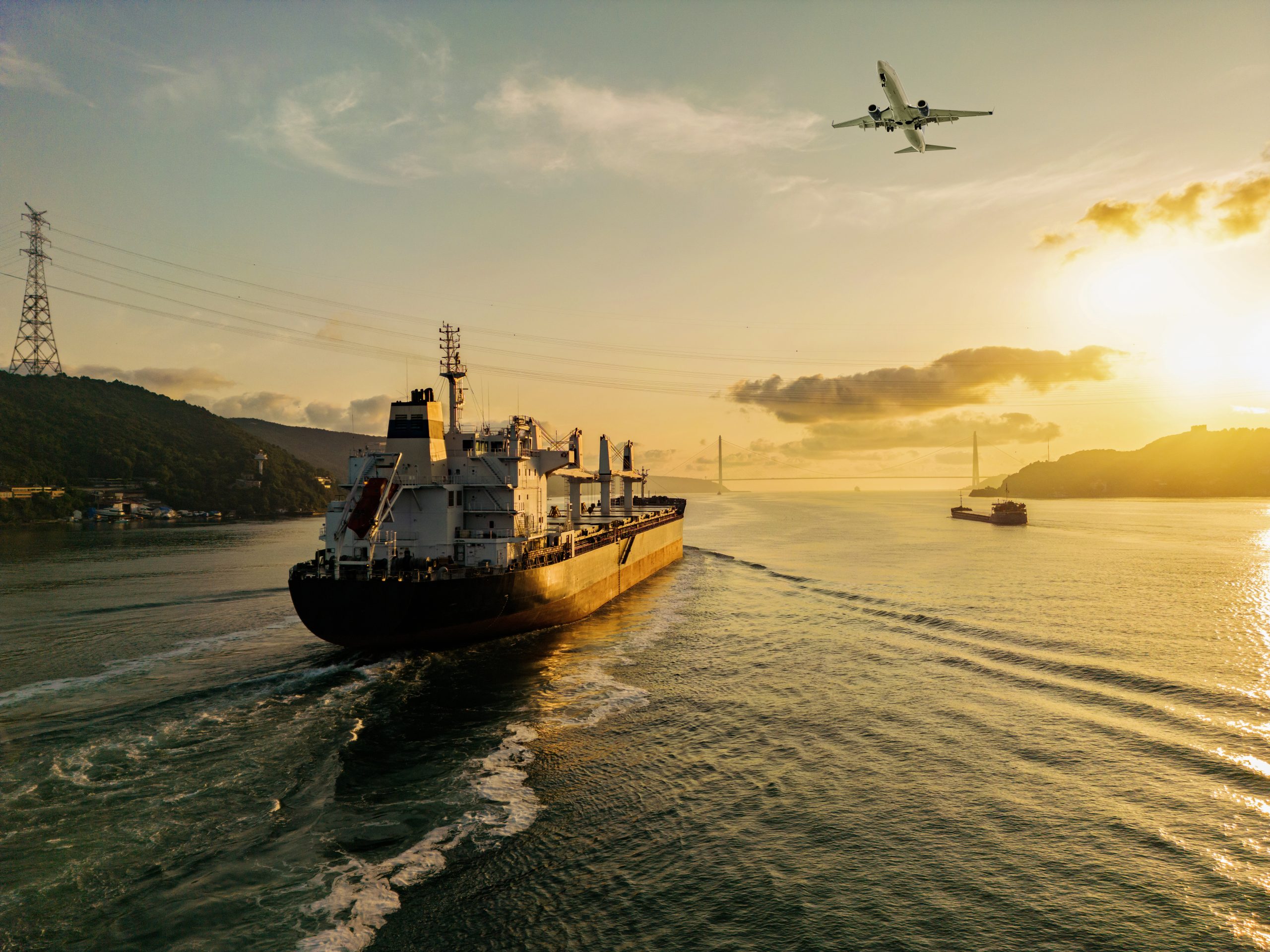 Cargo ship and plane at sunrise.