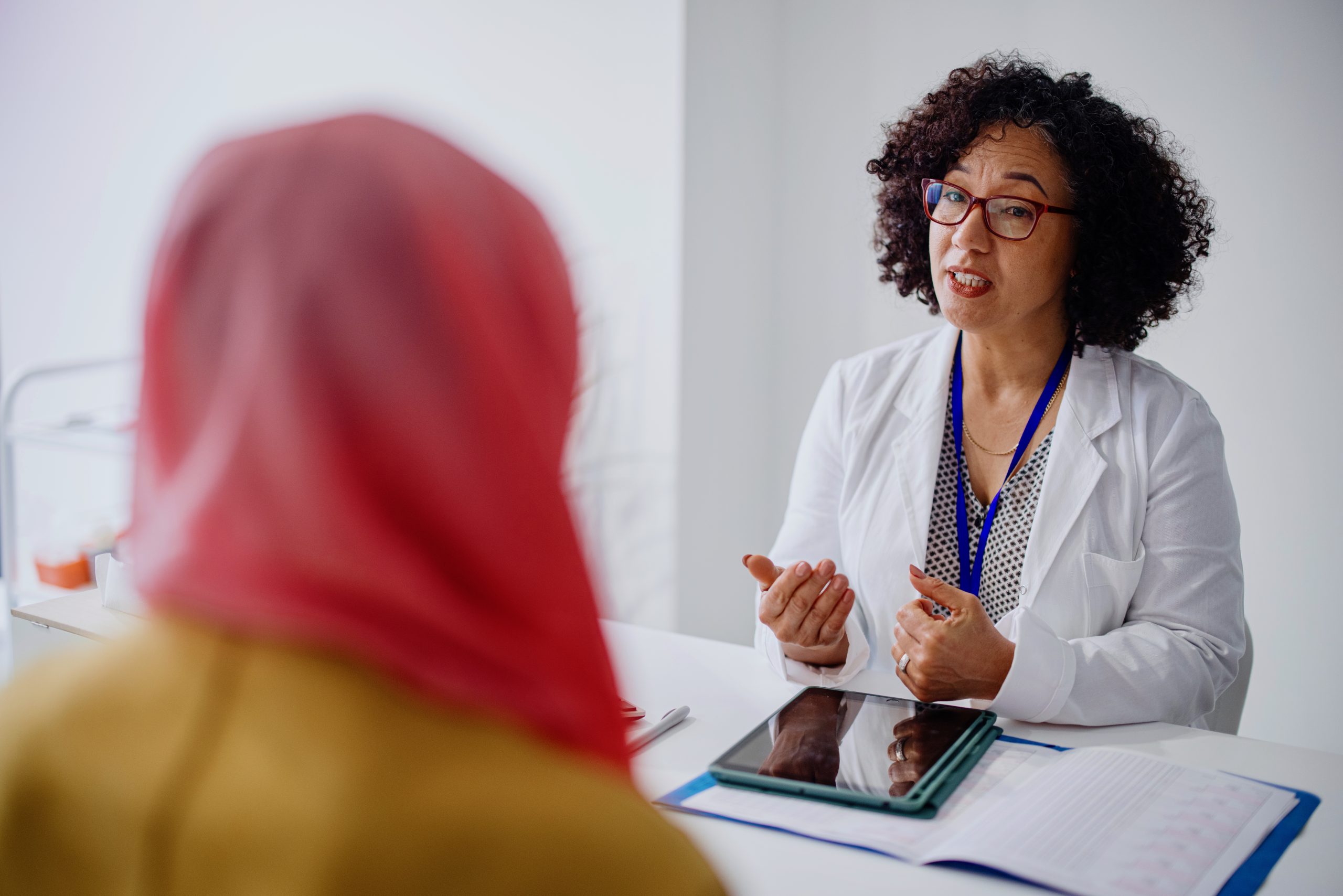 Healthcare professional talking to a patient with a head covering.