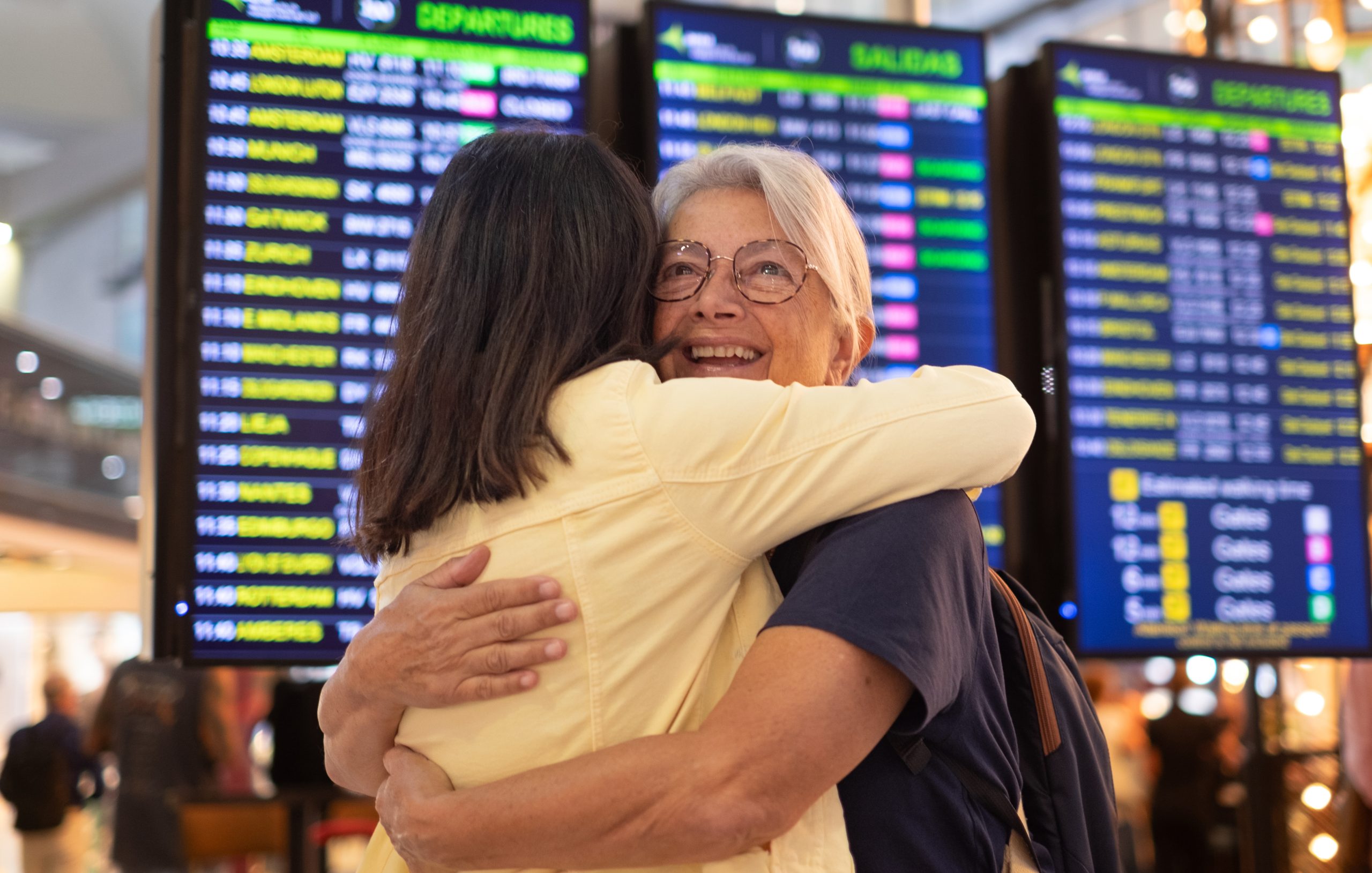 Two people hugging at an airport.