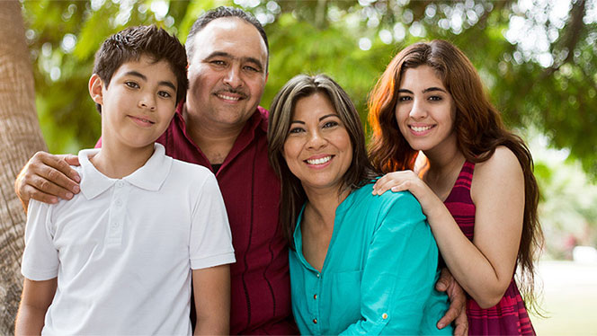 Adult woman and man with two adolescents, all smiling.